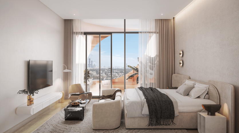 Une chambre moderne du One Residences dispose d'un grand lit avec des draps blancs et une couverture sombre. La chambre dispose d'une télévision fixée au mur, d'une petite table avec des objets décoratifs et d'un fauteuil près des baies vitrées offrant une vue imprenable sur le paysage urbain. Ambiance légère et aérée.