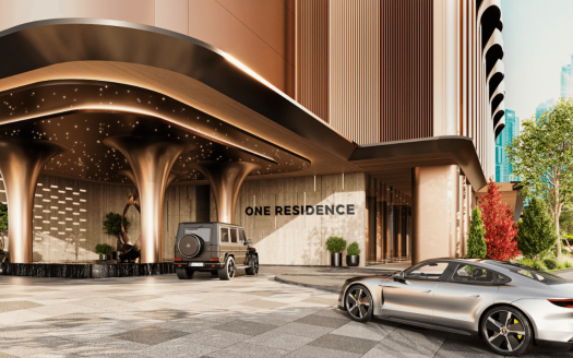 Une entrée luxueuse dans un immeuble résidentiel haut de gamme nommé « One Residences ». La scène présente une architecture contemporaine avec des colonnes épurées et un éclairage élégant. Un SUV noir et une voiture de sport argentée sont garés dans l’allée entourée d’une verdure luxuriante.