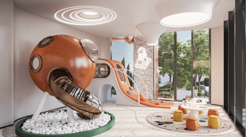 Une salle de jeux moderne pour enfants à One Residences comprend une structure futuriste de toboggan orange avec des fenêtres circulaires menant à une piscine à balles. L'espace dispose de grandes fenêtres, d'un coin salon confortable avec des tabourets colorés et d'une décoration fantaisiste comprenant des œuvres d'art murales et des tapis ludiques.