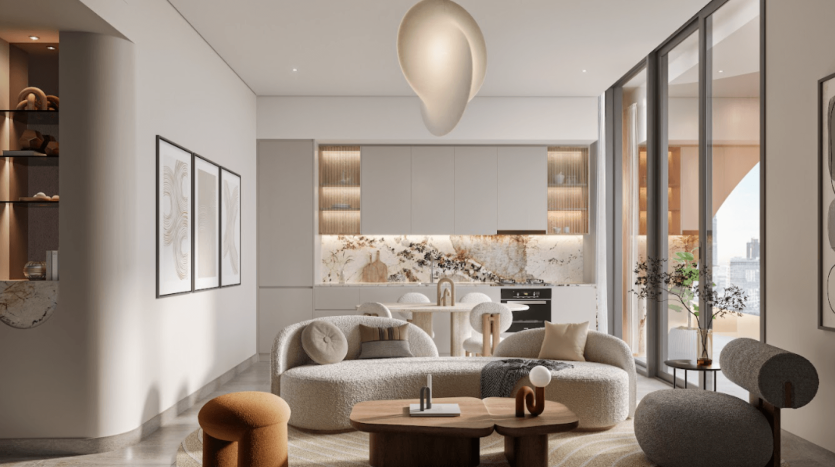 Salon moderne du One Residences avec de grandes fenêtres et une décoration beige. Comprend un mobilier contemporain, notamment un canapé sectionnel incurvé, une table basse ronde et des chaises d'appoint. La cuisine minimaliste avec dosseret en marbre est visible à l'arrière, mettant en valeur des armoires élégantes.