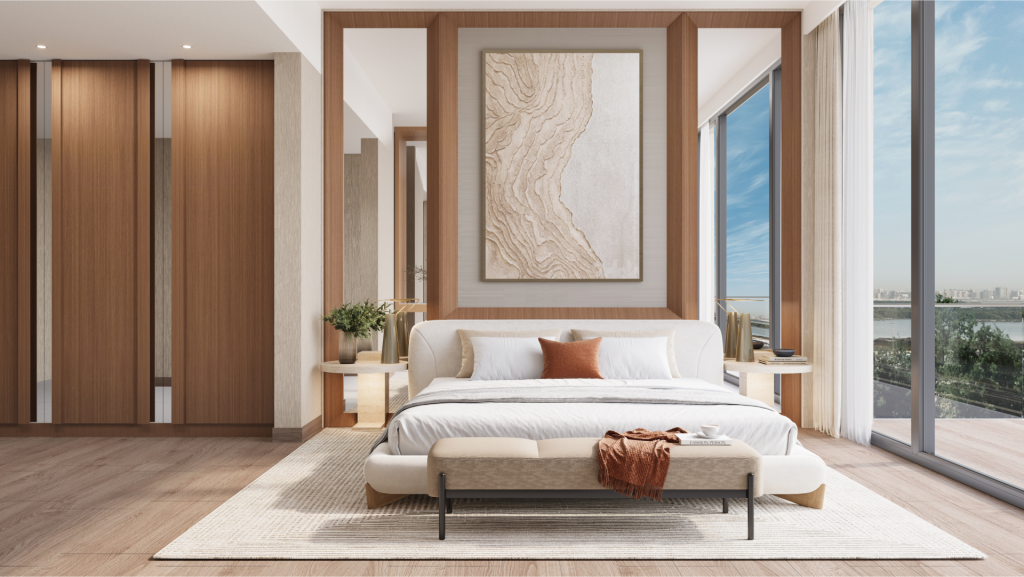 The modern bedroom at Belgrove Residences features a king-size bed with a white comforter and cushions set against a wooden headboard. Next to the bed are two matching bedside tables with plants. The room has bay windows offering a view of the sunny outdoor landscape.