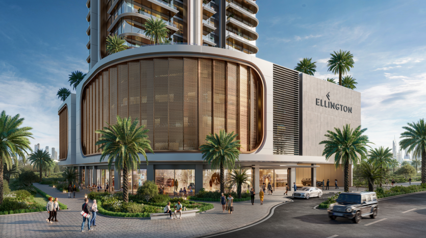 This image shows a modern building complex called Ellington, part of the elegant Belgrove Residences. It features a tall glass tower and an adjoining structure with large, rounded windows. Lush vegetation and palm trees surround the building, with people walking nearby and cars on the street.