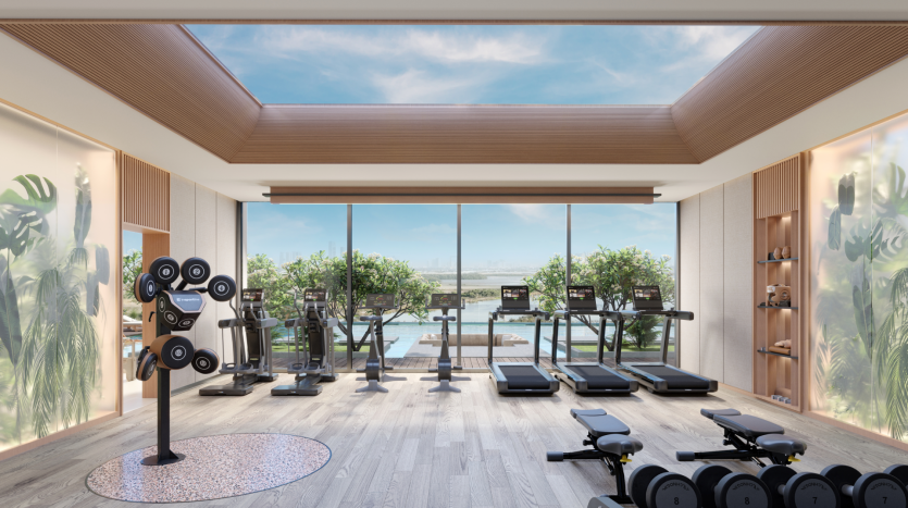 Belgrove Residences' modern gym features large windows with panoramic views of the outdoors, and is equipped with treadmills, weight machines and free weights. The space features wood accents, ceiling skylights and green plants, creating a bright and welcoming atmosphere.
