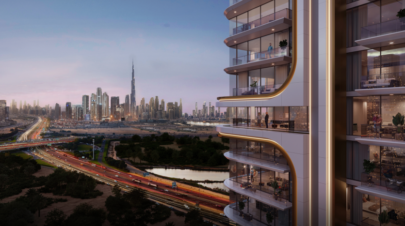 Belgrove Residences, a modern high-rise apartment building with illuminated balconies, overlooks a busy freeway and a green space at dusk. The cityscape in the background features numerous skyscrapers, including an iconic tall tower. The sky is a soft gradation from blue to pink.