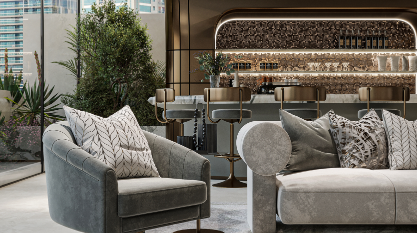 Un salon luxueux et moderne avec des fauteuils gris moelleux, un canapé gris orné de coussins à motifs et un espace bar élégant en arrière-plan. Le bar comprend des tabourets hauts, un dosseret en mosaïque et des étagères présentant divers objets. Les plantes d'intérieur ajoutent une touche de nature.