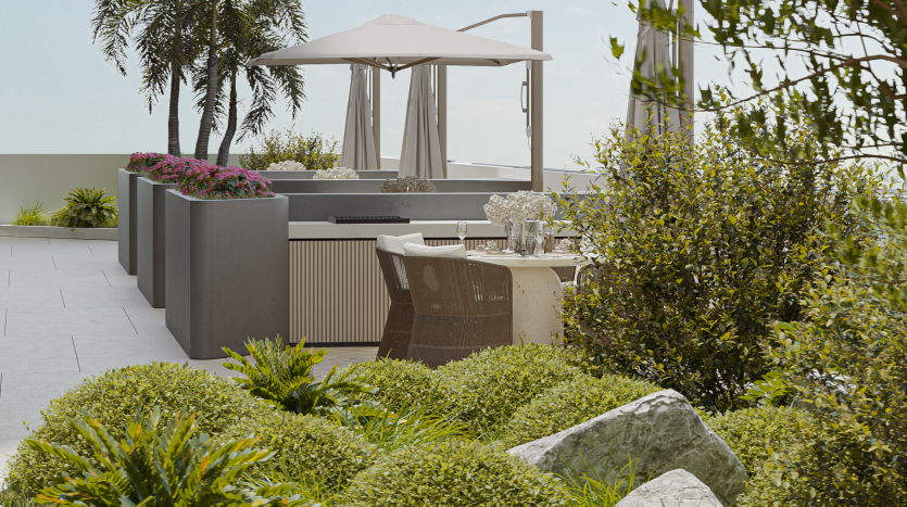 Le toit-terrasse comprend un coin repas avec une table et des chaises sous un grand parasol. La zone est entourée d'une verdure luxuriante, comprenant des buissons et des palmiers. L'espace est moderne, serein et donne sur un ciel dégagé.