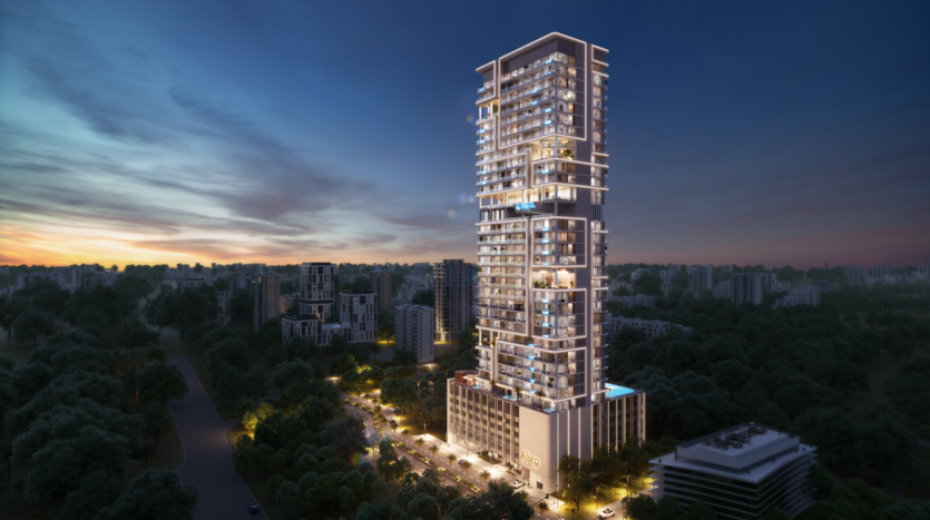 A modern, tall, illuminated skyscraper, designed by Allura Citi Developers, rises at dusk, surrounded by smaller buildings and lush green trees. The sky features warm sunset hues, reinforcing the mood of the urban landscape.
