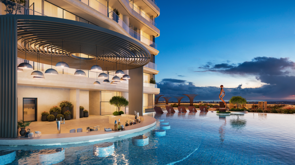 The luxurious sunset rooftop infinity pool, designed by Allura Citi Developers, is surrounded by modern architecture. Ambient lighting under a circular awning complements the pool bar with drinks and sun loungers with parasols. A striking statue adorns an island in the water.
