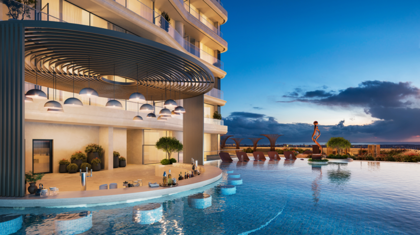 The luxurious sunset rooftop infinity pool, designed by Allura Citi Developers, is surrounded by modern architecture. Ambient lighting under a circular awning complements the pool bar with drinks and sun loungers with parasols. A striking statue adorns an island in the water.