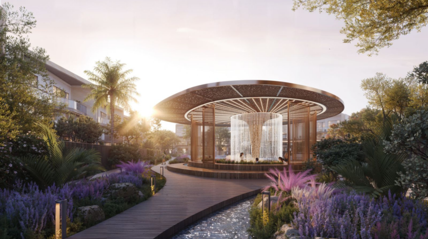 Une scène de jardin sereine avec un pavillon circulaire en bois au toit au design complexe. Une cascade d'eau se dresse au centre, entourée d'une végétation luxuriante et de fleurs violettes éclatantes. Un sentier en bois borde un ruisseau étroit menant au pavillon.