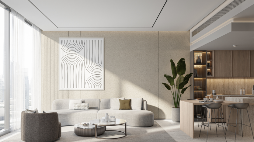 Un salon moderne du One Beverly Dubai présente des éléments de design minimalistes, notamment un canapé beige incurvé, une table basse ronde et de grandes œuvres d'art murales abstraites. Une plante en pot est placée à côté d'un petit comptoir de bar avec des tabourets, et des fenêtres pleine longueur permettent à la lumière naturelle d'inonder l'espace.