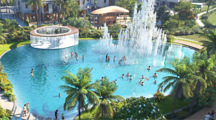 Sun City dispose d'un parc aquatique animé avec de nombreuses personnes nageant et jouant dans une grande piscine bleu clair. Des fontaines décoratives projettent de hauts jets d'eau, tandis que des palmiers tropicaux entourent la zone, complétée par des bâtiments modernes en arrière-plan.