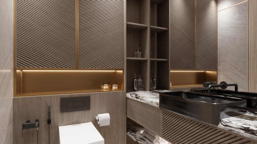 Une salle de bain moderne au Binghatti Royale avec des armoires en bois aux motifs diagonaux, des comptoirs en marbre et des luminaires élégants. Le lavabo est noir avec un robinet assorti et les murs ont un éclairage d'ambiance intégré. Les toilettes sont accompagnées d'un pulvérisateur de bidet et d'un porte-papier hygiénique.