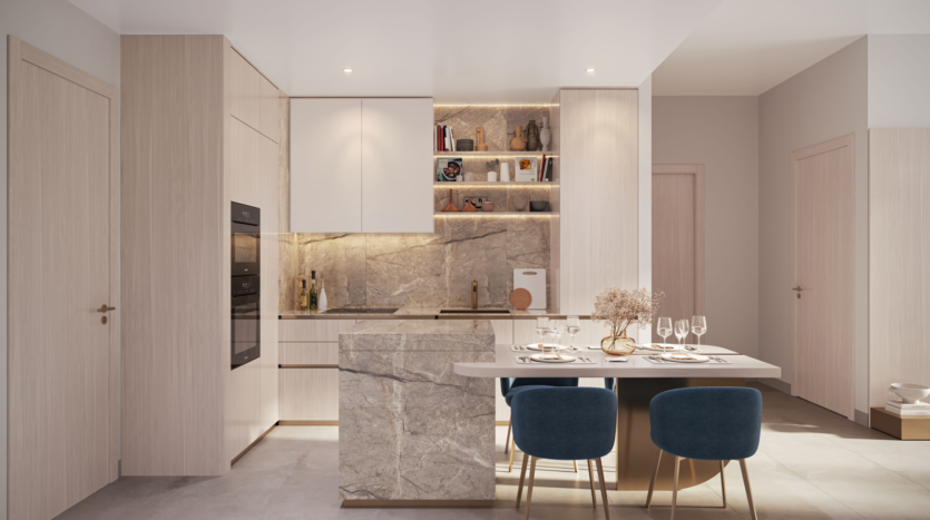 A modern kitchen with light wood cabinets, built-in oven and marble countertops embodies the Legado Prescott style. A small dining area includes a marble table with plates and glasses, surrounded by blue chairs. Subtle lighting enhances the clean, contemporary design.