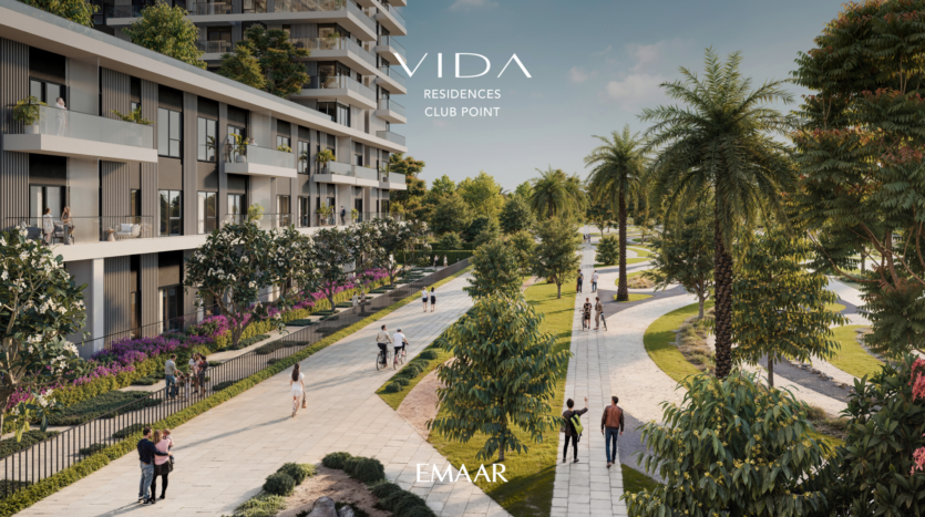 Un immeuble résidentiel moderne, Vida Residences at Club Point, dispose d'une grande allée bordée de palmiers et de verdure. Les gens se promènent le long du chemin sous un ciel clair. L'image comporte le texte : « Vida Residences Club Point » et « Emaar.