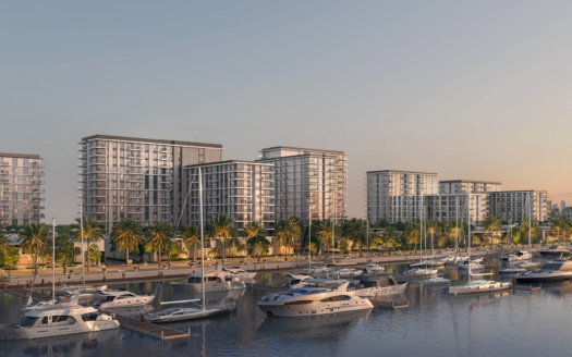 Une rangée d'appartements modernes en hauteur avec balcons surplombe une marina remplie de yachts à Pierpoint. Des palmiers bordent le front de mer et l'horizon lointain de la ville est visible dans un ciel clair en soirée.