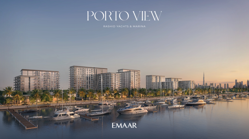 Une marina avec plusieurs yachts amarrés dans des eaux calmes, bordée d'immeubles d'appartements modernes. Un ciel de coucher de soleil projette une lueur chaleureuse sur la scène, avec un horizon urbain lointain visible en arrière-plan. Le texte indique « Porto View » et « Rashid Yachts & Marina » par Emaar.