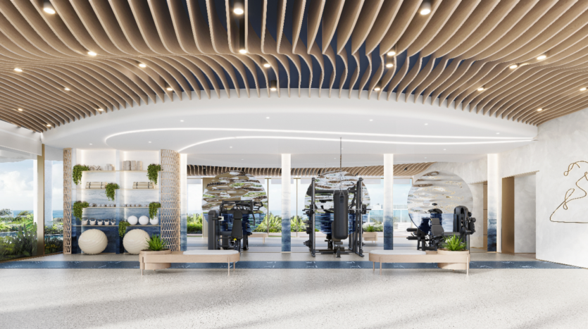 Une salle de sport moderne et spacieuse à Sunset Bay avec des accents de plafond en bois, de grands miroirs, des appareils d'exercice et des ballons de fitness. Les baies vitrées révèlent une vue panoramique sur l'extérieur. Des plantes décoratives rehaussent l'atmosphère aérée et accueillante.