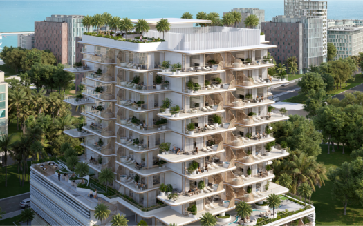 Un immeuble d'appartements moderne à plusieurs étages entouré d'arbres et doté de grands balcons verdoyants se dresse fièrement près de Sunset Bay. La structure offre un aperçu de l'océan en arrière-plan, en harmonie avec les autres bâtiments voisins le long du front de mer tranquille.