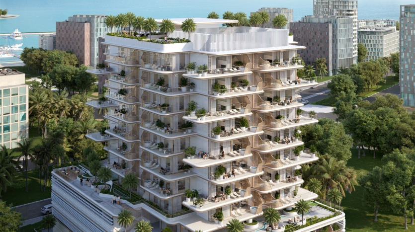 Un immeuble d'appartements moderne à plusieurs étages entouré d'arbres et doté de grands balcons verdoyants se dresse fièrement près de Sunset Bay. La structure offre un aperçu de l'océan en arrière-plan, en harmonie avec les autres bâtiments voisins le long du front de mer tranquille.