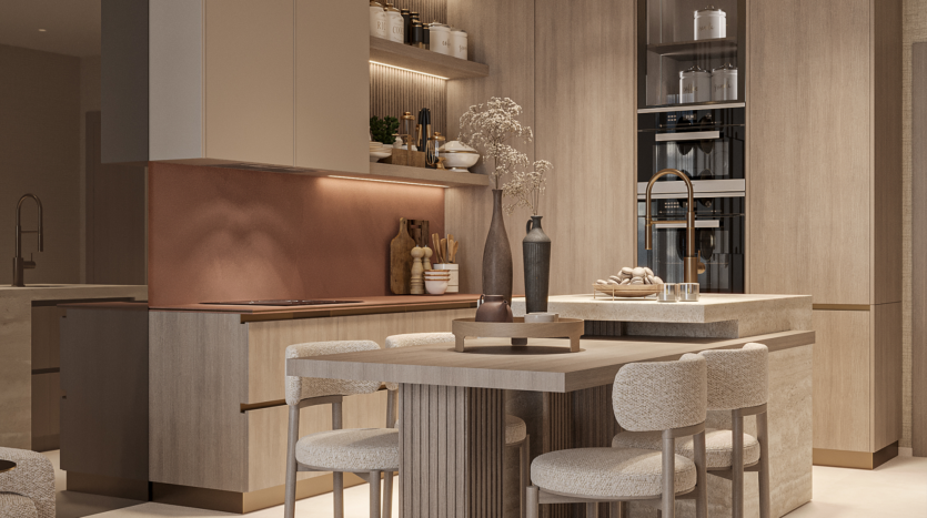 A modern kitchen with light wood cabinets, copper backsplash and built-in oven. The central island features a matching dining area with beige upholstered chairs. Decorative objects and dried flowers add warmth to the space.