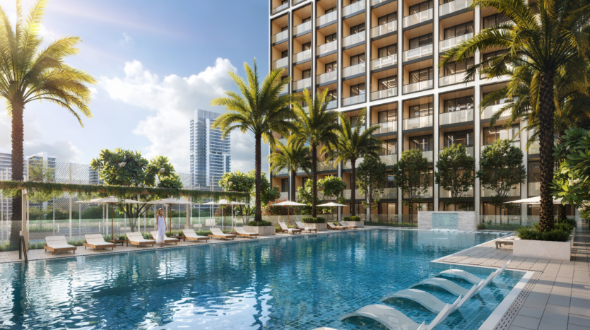 Une grande piscine extérieure, dégageant une ambiance d'élite, est entourée de palmiers et de chaises longues devant un grand immeuble d'appartements Binghatti. Le ciel est clair et ensoleillé, avec un horizon urbain moderne en arrière-plan. Une personne se tient debout au bord de la piscine.