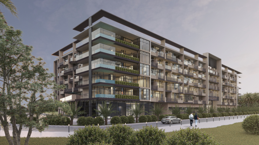 A modern six-storey building with glass balconies and greenery. A person is walking along the path and a car is parked nearby. The scene takes place under a cloudy sky and is surrounded by trees and bushes.