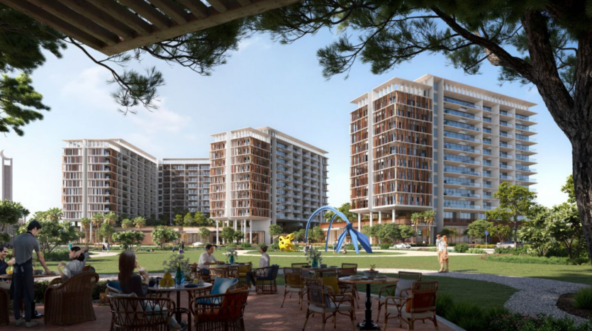 Les gens sont assis sur une terrasse avec des tables au premier plan, profitant d'une vue sur le paysage verdoyant et luxuriant de Parkfive et ses arbres imposants. Des immeubles modernes de grande hauteur et une aire de jeux colorée peuvent être vus en arrière-plan sous un ciel bleu clair.