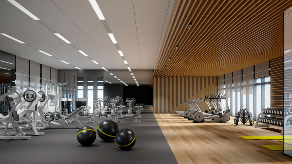 Parkfive propose une salle de sport moderne avec des équipements d'exercice, notamment des tapis de course, des appareils de musculation et des ballons d'exercice. La salle est dotée d'un mélange de parquet et de revêtement de sol en caoutchouc, avec une abondante lumière naturelle qui pénètre à travers de grandes fenêtres sur un côté.