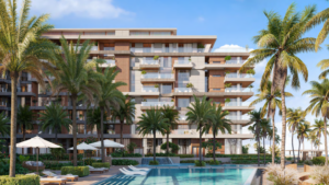 Ellington Cove è un moderno resort costituito da un edificio rettangolare con balconi circondato da alte palme. In primo piano si trova una grande piscina attrezzata con lettini e ombrelloni, il tutto sotto un cielo azzurro e limpido.