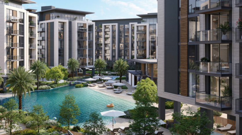 View of a luxury apartment complex in Belgrave, with tall buildings surrounding a large swimming pool. The area is landscaped with palm trees, lush gardens and several sun loungers and parasols set around the pool.