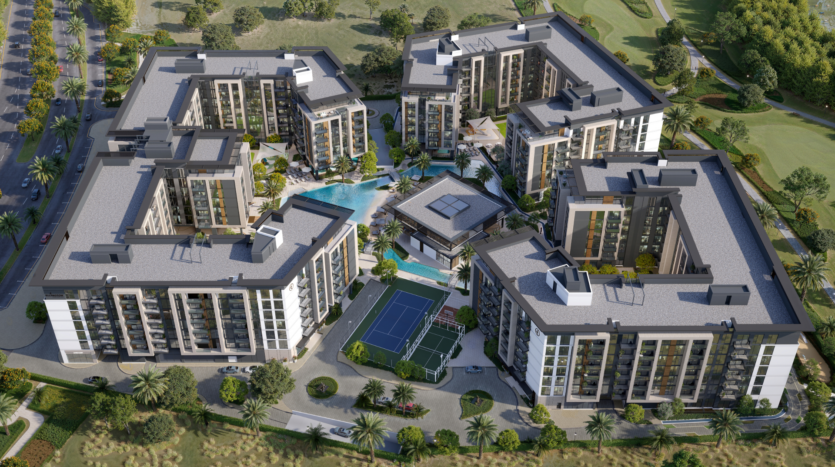 Aerial view of a residential complex comprising six multi-storey buildings arranged around a central courtyard. The courtyard includes a swimming pool, landscaped gardens and a tennis court. The surroundings are lush with trees and greenery.