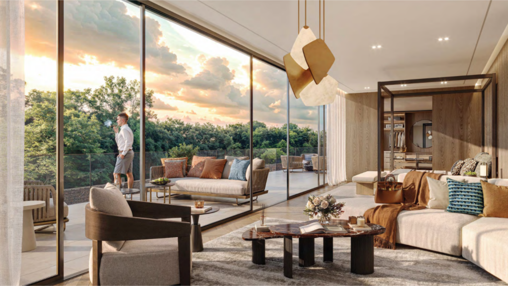 Salon moderne avec de grandes portes vitrées ouvrant sur un patio. Une personne se tient dehors en train de profiter du coucher de soleil. À l'intérieur, on trouve des canapés contemporains, une table basse en bois Bo Monde et des plafonniers abstraits. La scène suggère une atmosphère cosy et haut de gamme.