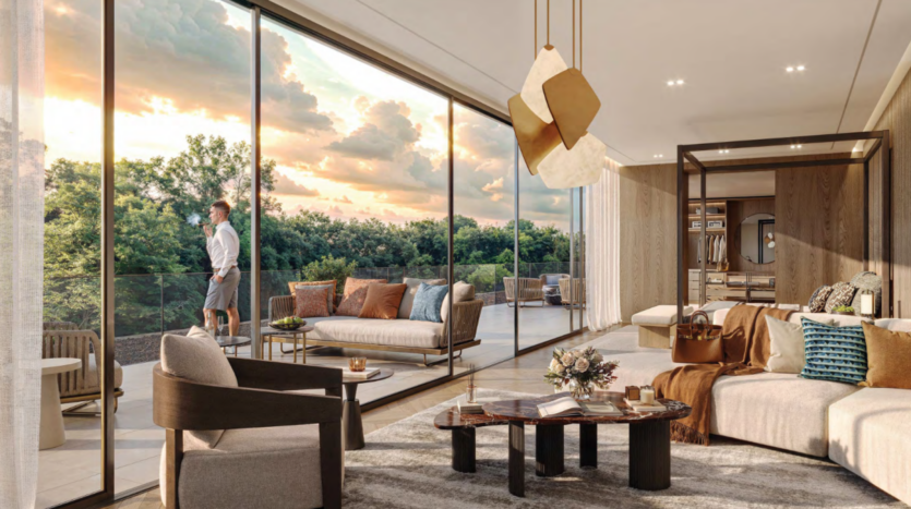 Salon moderne avec de grandes portes vitrées ouvrant sur un patio. Une personne se tient dehors en train de profiter du coucher de soleil. À l'intérieur, on trouve des canapés contemporains, une table basse en bois Bo Monde et des plafonniers abstraits. La scène suggère une atmosphère cosy et haut de gamme.