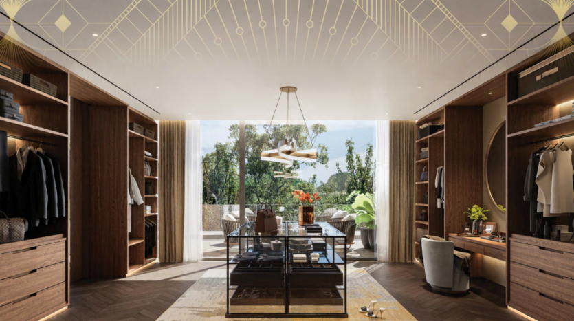 Découvrez le style de vie Bo Monde dans ce luxueux dressing aux finitions en bois, doté d'armoires ouvertes et d'une table d'exposition centrale en verre. Un lustre est suspendu au-dessus, tandis que de grandes fenêtres révèlent une végétation luxuriante. Un coin salon et un bureau sont élégamment positionnés sur le côté droit.