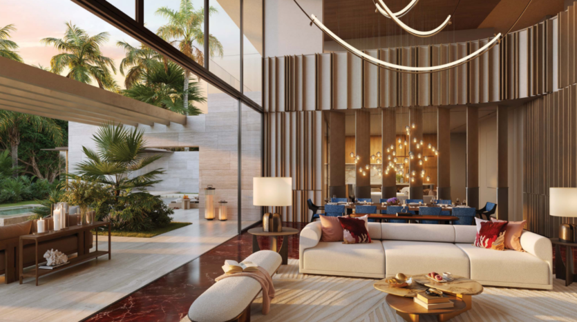 Un salon moderne avec de hauts plafonds et de grandes fenêtres s'ouvre sur un patio avec des palmiers, capturant l'essence de l'élégance Bo Monde. L'espace comprend un élégant canapé beige, un sol en marbre rouge, des accents en bois et une table à manger avec un lustre, créant une ambiance luxueuse et ouverte.
