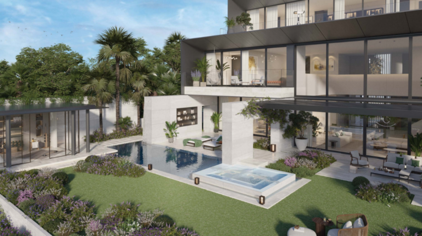 Une villa de luxe moderne signée Bo Monde dispose d'une façade en verre donnant sur une piscine rectangulaire et un jardin luxuriant. L'espace extérieur comprend de la verdure, un coin salon et un petit bar. De grandes fenêtres offrent un aperçu de l'intérieur élégant.