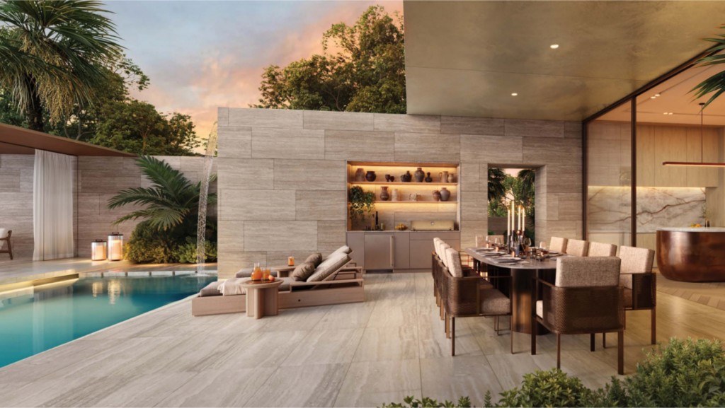 Le luxueux espace extérieur Bo Monde comprend une longue table à manger dressée pour le dîner près de la piscine. Des chaises longues beiges font face à l'eau, entourées d'éléments de design modernes tels que des murs en pierre et des palmiers, le tout doucement éclairé par le ciel crépusculaire.