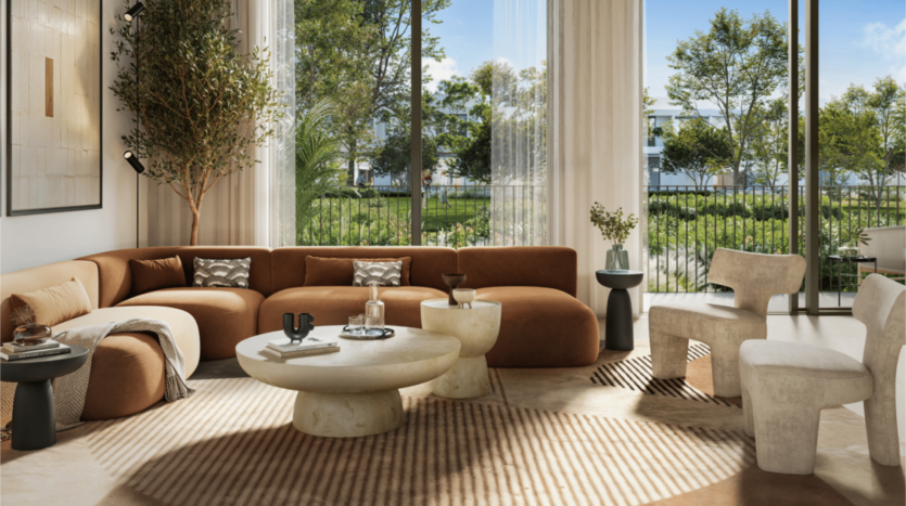 Un soggiorno moderno con un grande divano angolare marrone, tavolini rotondi e sedie beige esprime lo stile sofisticato di Kaia. Le ampie finestre offrono una vista sul giardino alberato, mentre i toni della terra e un tappeto strutturato esaltano l'atmosfera calda.