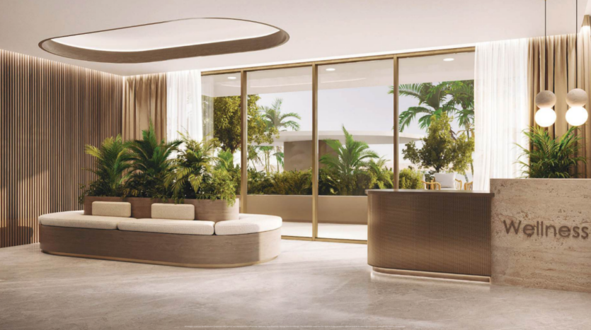 Modern wellness center lobby with neutral palette. Features a curved reception counter labeled "Wellness", a lounge area with white cushions, indoor plants and large windows highlighting the greenery outside. Soft lighting creates a calm ambience.