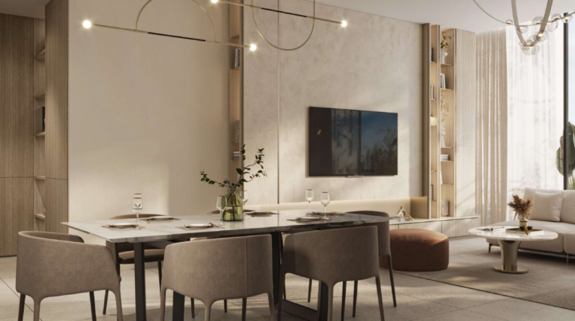 Una sala da pranzo moderna con un tavolo in marmo per quattro persone, sedie marroni e un lampadario minimalista appeso sopra. Un televisore a parete si affaccia su uno spazio confortevole con un tavolo rotondo e sedute imbottite. I toni neutri e le tende velate completano l'arredamento elegante.