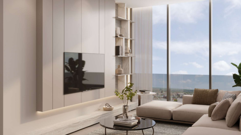 Soggiorno moderno con un'ampia finestra che offre una vista sulla città. Include un televisore a parete, un divano angolare beige chiaro con cuscini, un tavolino in vetro con una pianta e decorazioni minimaliste su scaffali. La luce naturale riempie lo spazio.