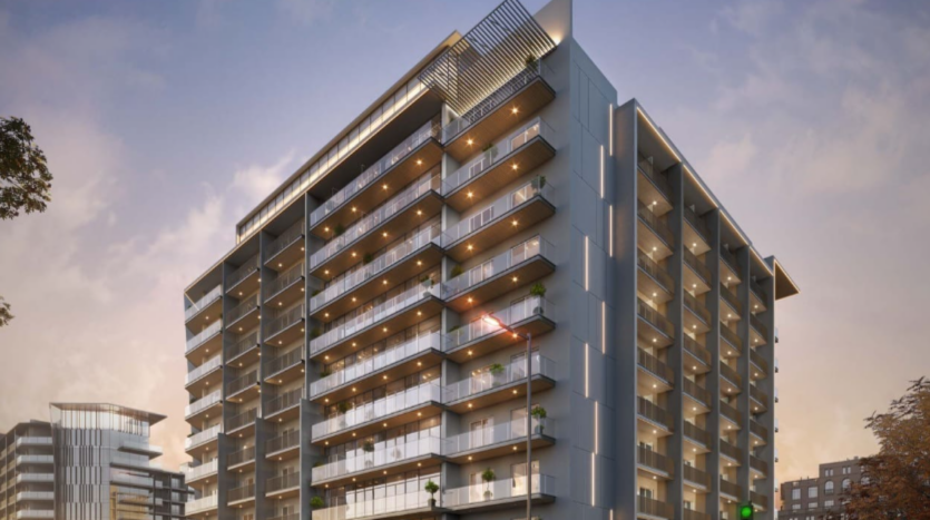 Floarea Grande è un moderno edificio residenziale a più piani con diversi balconi, luci luminose e un disegno geometrico in cima. Sullo sfondo del cielo notturno, la sua eleganza è completata da altri edifici visibili in lontananza.