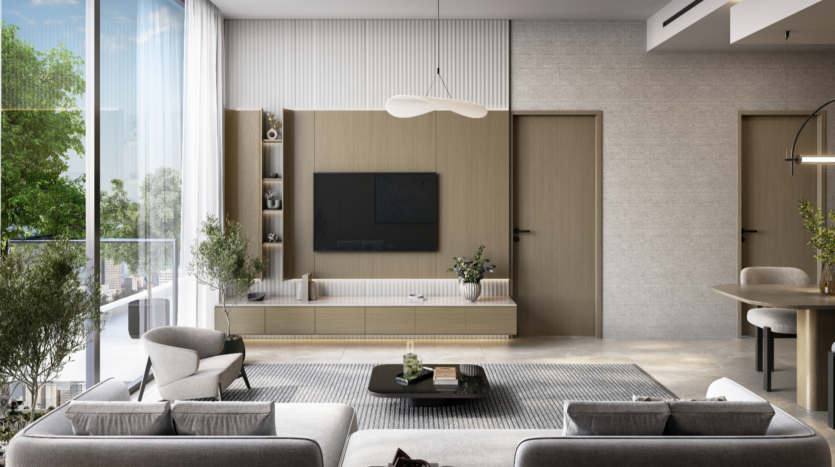 A modern living room in neutral tones enhances Verano's elegance, with two gray sofas facing a flat-screen TV mounted on a wooden wall unit. A textured rug covers the floor, and a coffee table sits in the center. Large windows offer a view of the greenery outside.