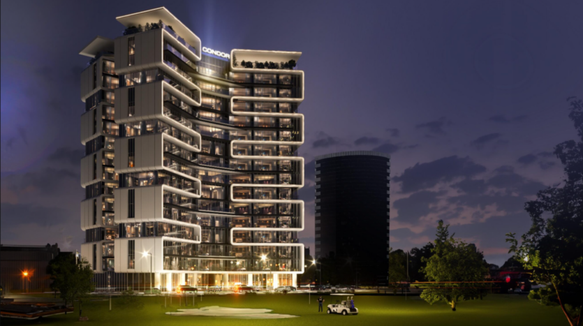 Un bâtiment moderne à plusieurs étages avec des sections éclairées se dresse au crépuscule sur un ciel qui s'assombrit, rappelant la beauté sereine d'un terrain de golf. Les balcons aux formes uniques ajoutent à son charme, tandis qu'au premier plan, une petite voiturette de golf est garée sur une zone herbeuse avec des arbres à proximité.