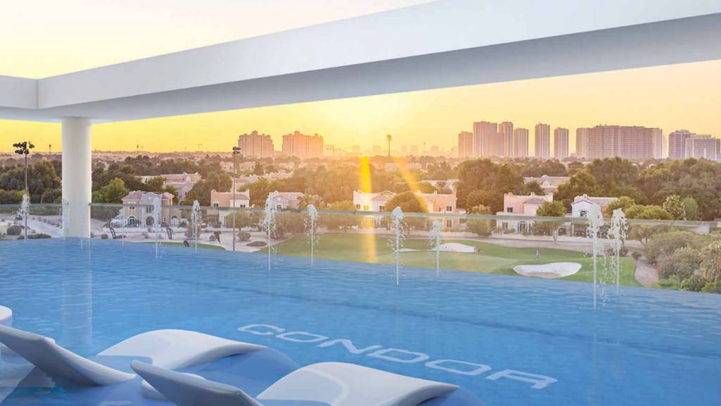 Une piscine à débordement sur le toit surplombant un paysage urbain au coucher du soleil, avec un horizon de grands immeubles et des arbres et des maisons au premier plan. Les chaises longues sont partiellement immergées dans la piscine sous un ciel lumineux, ressemblant à des endroits sereins que l'on trouve sur des parcours de golf exclusifs.