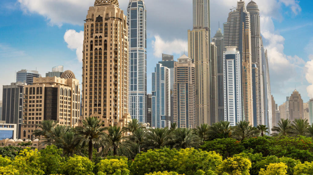 Un paysage urbain avec de nombreux gratte-ciels modernes, présentant un mélange de styles architecturaux rappelant Dubaï. Au premier plan, une végétation luxuriante et des palmiers s'épanouissent sous un ciel bleu partiellement nuageux, évoquant une oasis sereine au milieu de la grandeur urbaine.