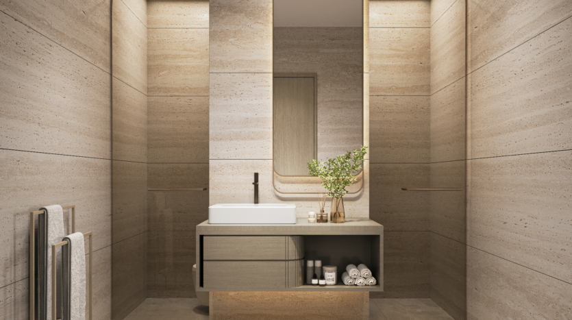 A modern, minimalist bathroom with beige stone walls and a touch of Verano elegance features a central vanity. It includes a rectangular mirror, white sink, black faucet, towels, toiletries and a vase with green leaves. Vertical lighting enhances the serene space.