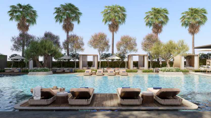 La lussuosa piscina all'aperto del Mr C's, situata nel centro città, è dotata di lettini e cabanas, circondati da palme e piante fiorite. Asciugamani e cappello sono appoggiati sui lettini, mentre il cielo rimane limpido e azzurro.
