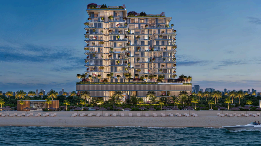 Un moderno edificio sul mare con numerosi balconi e una vegetazione rigogliosa sul tetto e su diversi livelli. La scena si svolge al crepuscolo, con le luci che illuminano la struttura. In primo piano una spiaggia sabbiosa e un mare calmo, con una barca nelle vicinanze.